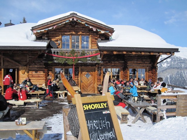 2010 Davos - Klosters: Holzhuette mit Sonnenterrasse und Angebotstafel im Schnee