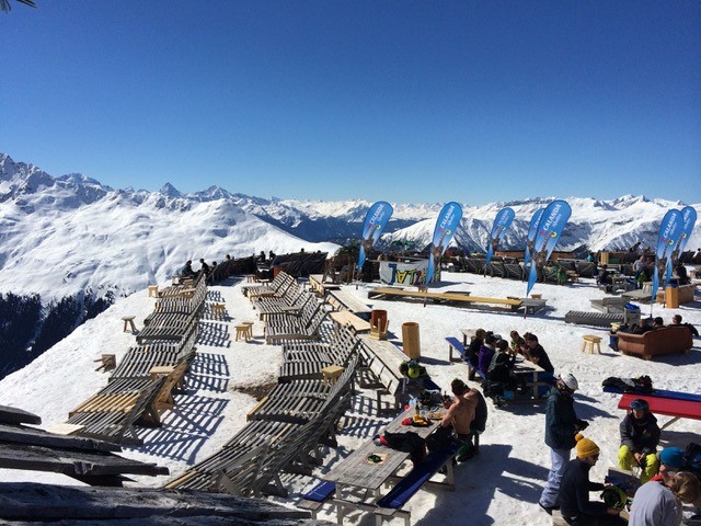 2014 Davos - Frauenkirch: Liegestuehle auf einer Bergterrasse, Skifahrer im Hintergrund