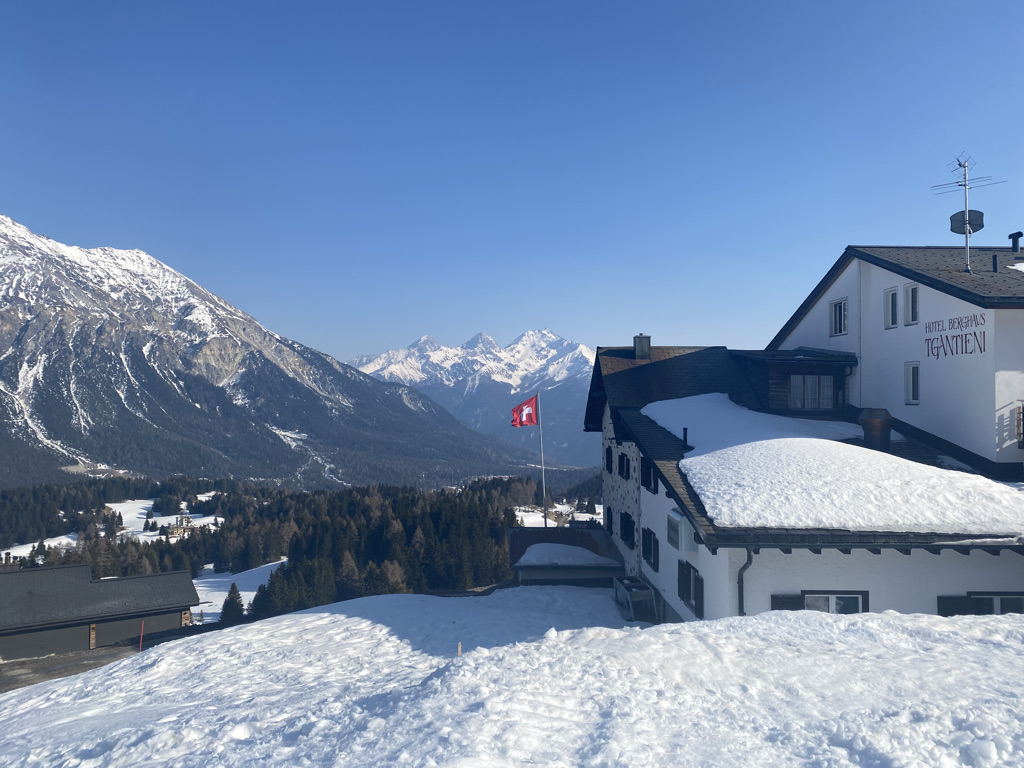 2022 Lenzerheide/Arosa: Weisses Gruppenhaus mit Fahnenmast in verschneiter Landschaft